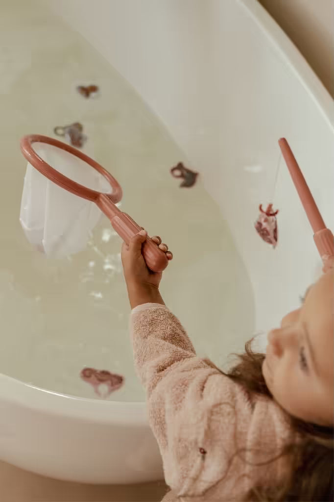 Kind tilt schepnet met Little Dutch badspeelgoed visspel Girl terwijl zeedieren in het bad drijven.