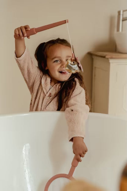 Lachend meisje vist met hengel uit Little Dutch badspeelgoed visspel Girl en vangt kleurrijk zeedier in bad.