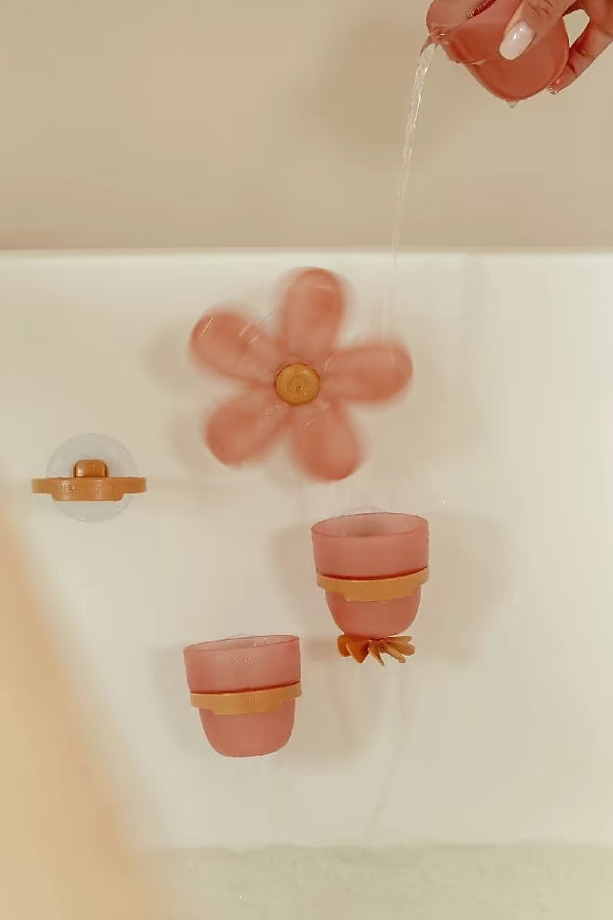 Kind giet water in Little Dutch Badwand bekers bloem, kleurrijk badspeelgoed dat draaien en spelen stimuleert.