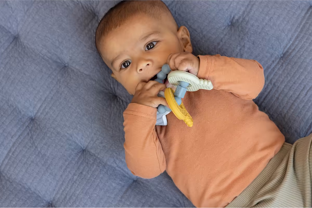 Baby kauwt op Little Dutch Bijtring sleutelbos in blauw, wit en geel, zacht bijtspeeltje en sensorisch speelgoed.