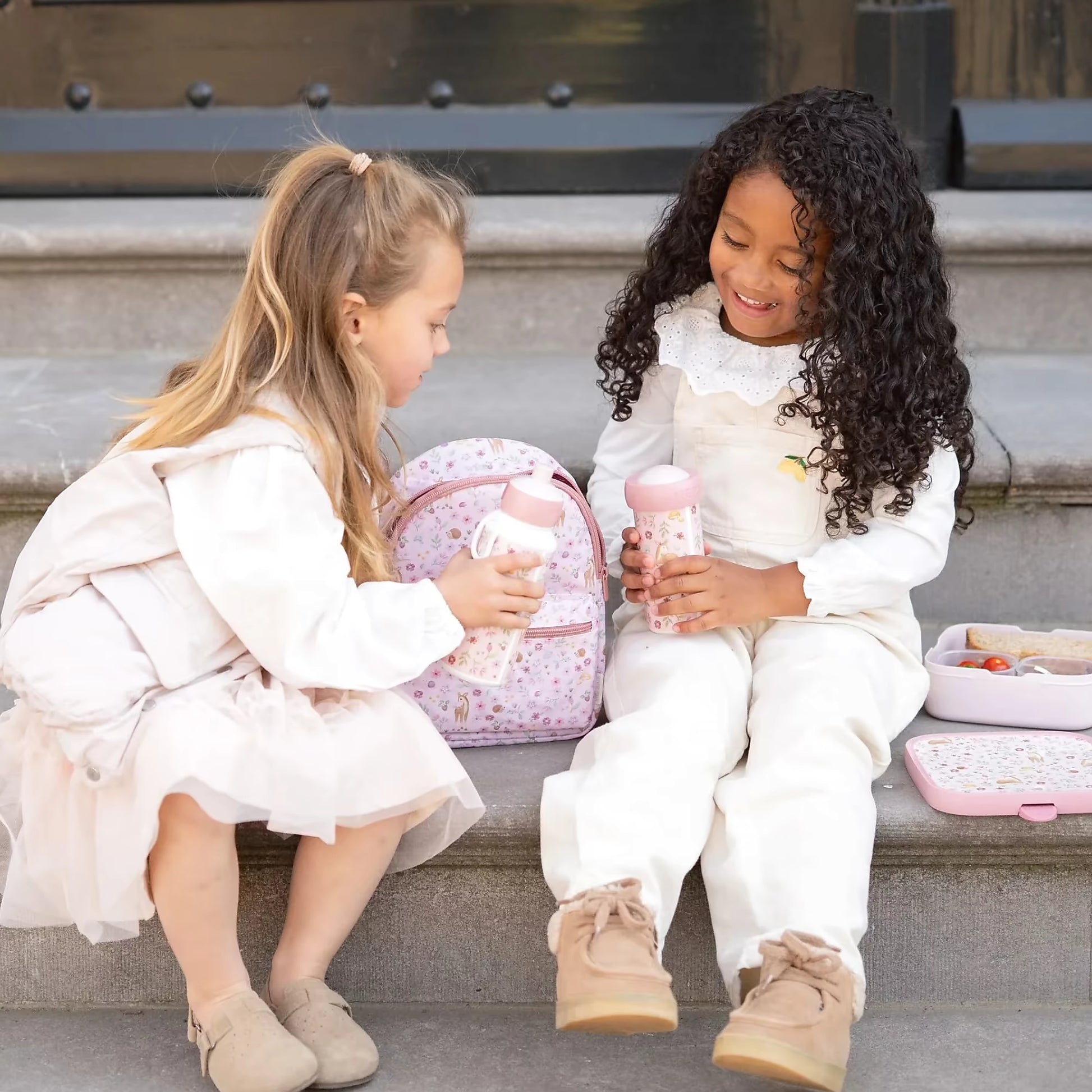 Twee kinderen met Little Dutch drinkfles Fairy Garden van Mepal, roze design met bloemen en dieren, schoolmoment.