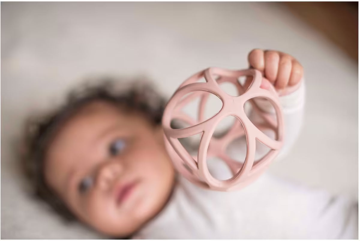 Baby houdt Little Dutch Grijpbal roze vast, zachte bijtringen en sensorisch speelgoed voor spel en ontwikkeling.