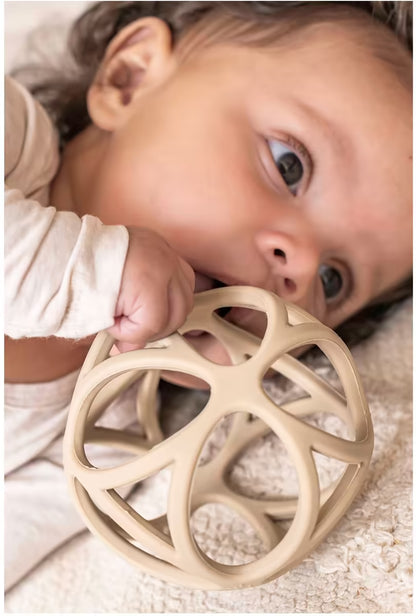 Baby speelt en bijt op Little Dutch Grijpbal Zand, veilig bijtring baby en sensorisch speelgoed.