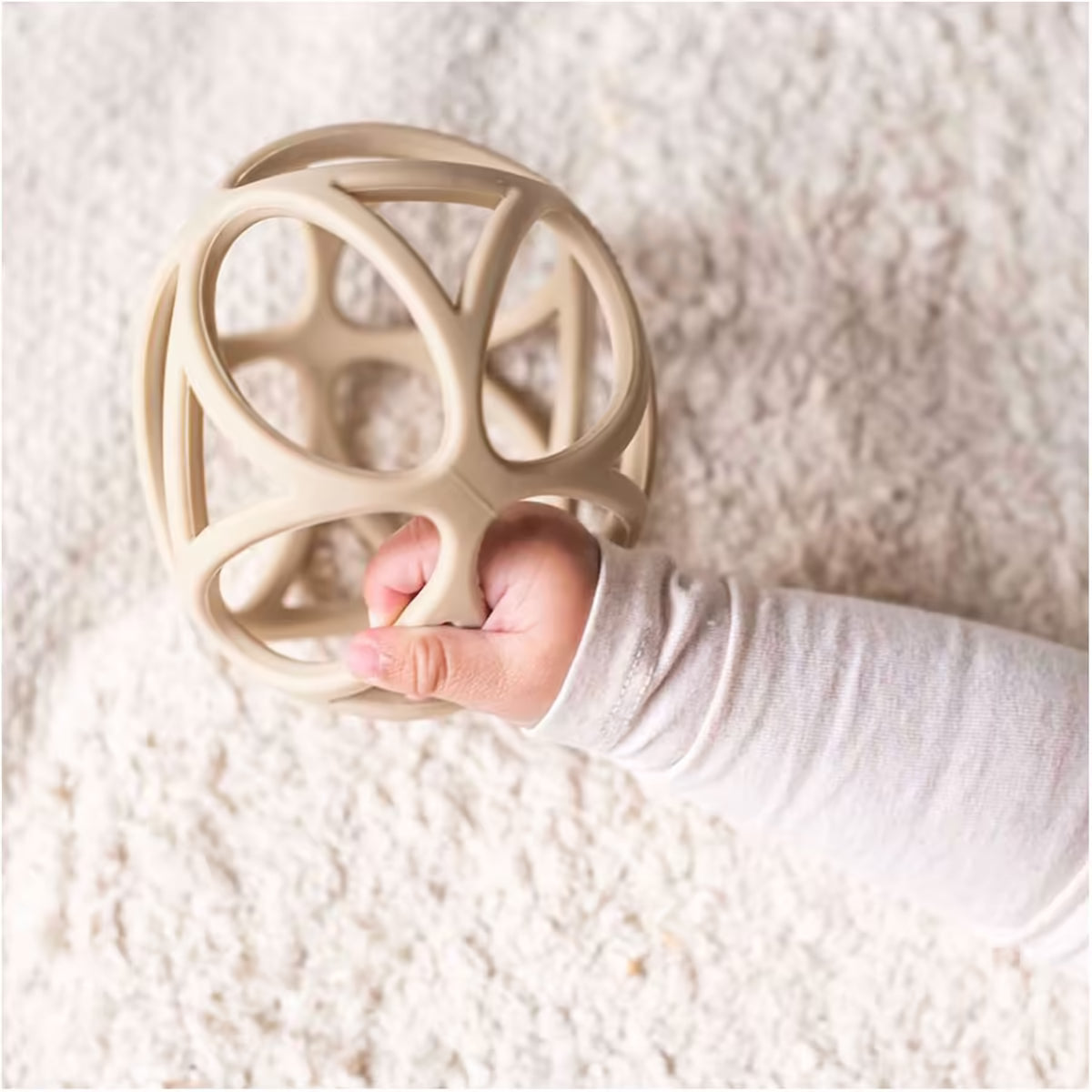 Babyhand houdt Little Dutch Grijpbal Zand stevig vast, ideaal bijtspeeltje en baby speelgoed.