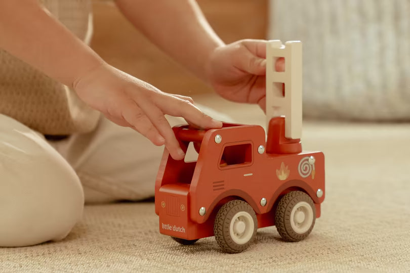 Kind speelt met Little Dutch houten brandweerwagen met ladder, duurzaam baby speelgoed voor peuters.