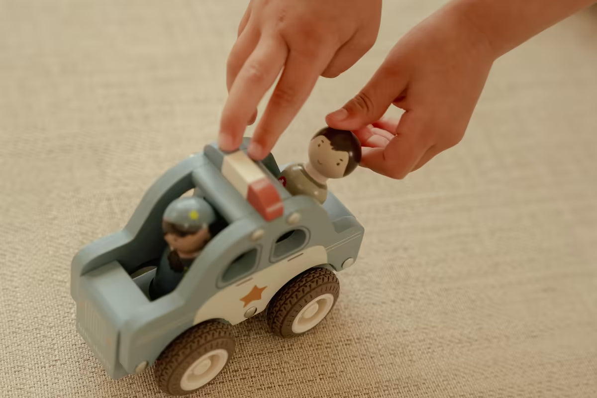 Kind speelt met Little Dutch houten politiewagen en pegdoll poppetjes, stevig speelgoed hout voor peuters.
