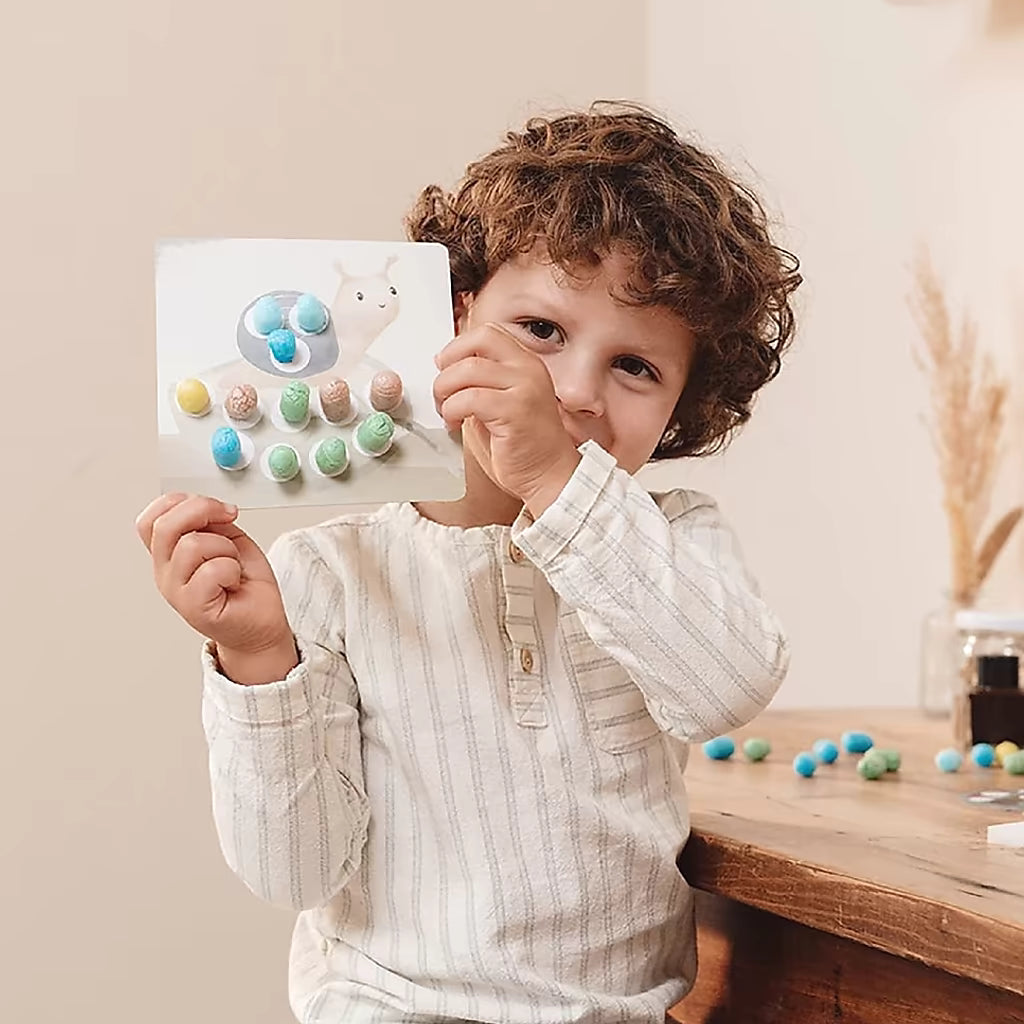 Peuter toont trots een slak gemaakt met de Little Dutch Knutseldoos Forest Friends, ideaal voor knutselen met peuters.