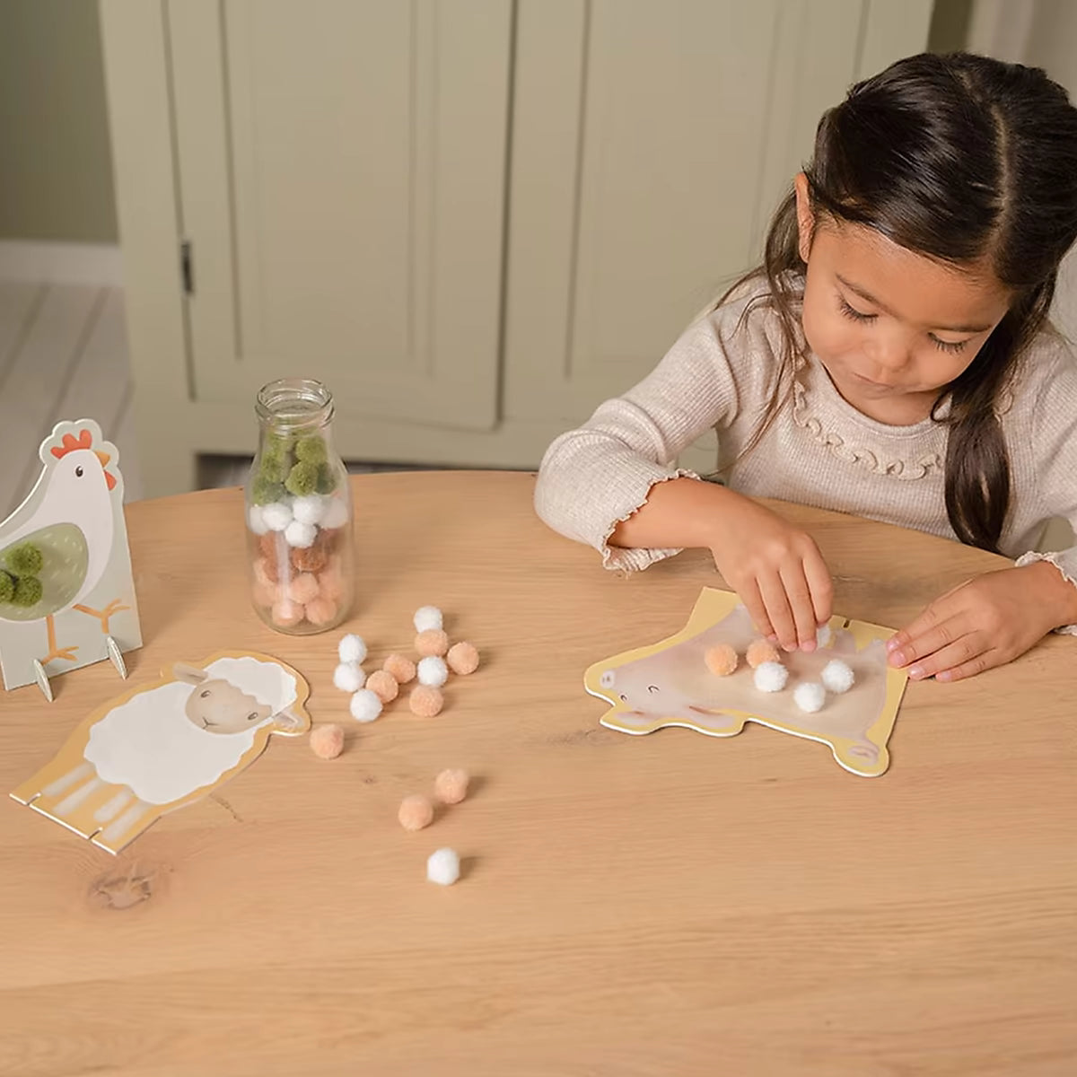 Meisje knutselt met Little Dutch pompom Little Farm dieren, een speels en leerzaam knutsel idee voor peuters.
