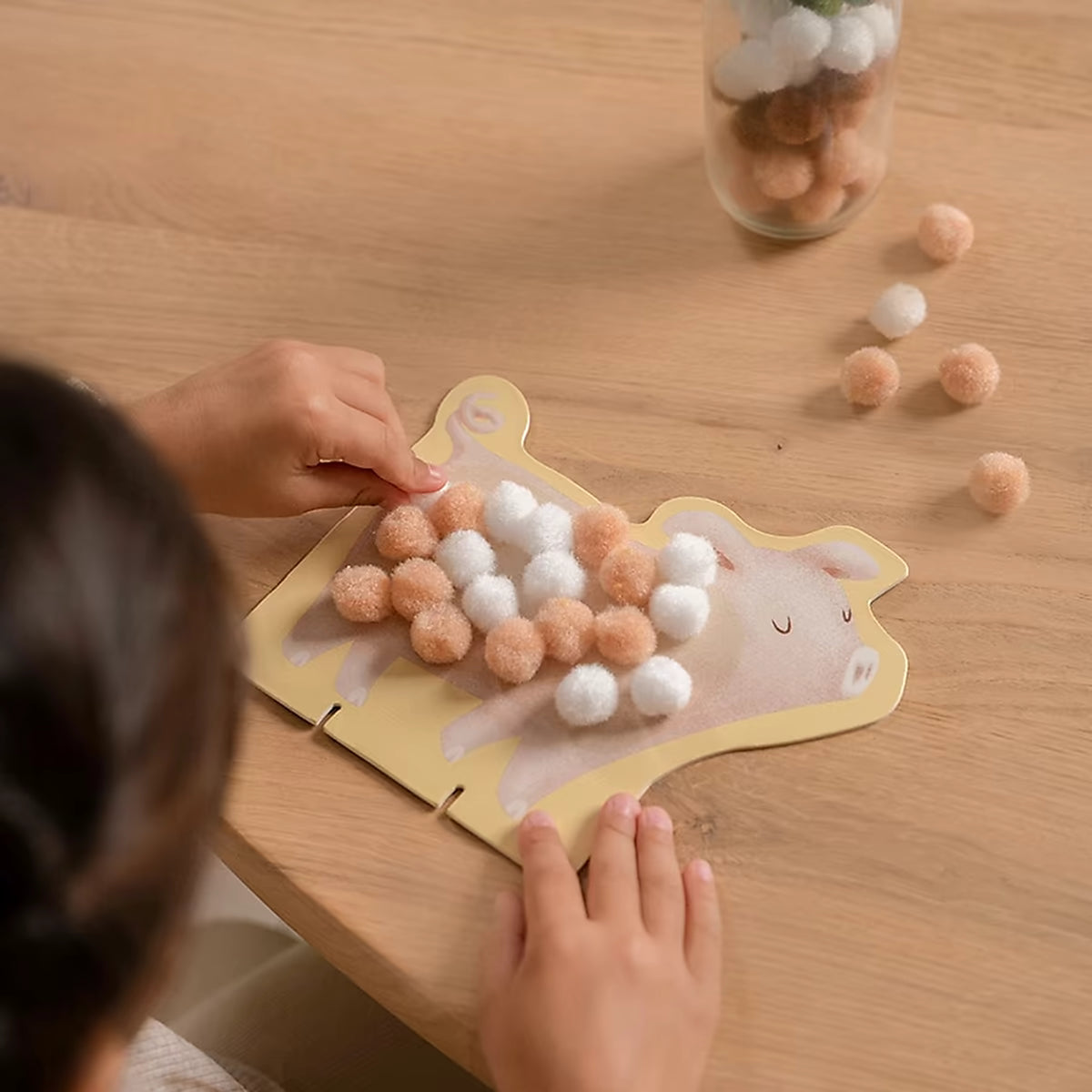 Kind plakt Little Dutch pompom op varken kaart, ideaal om te knutselen met peuters en jonge kinderen.