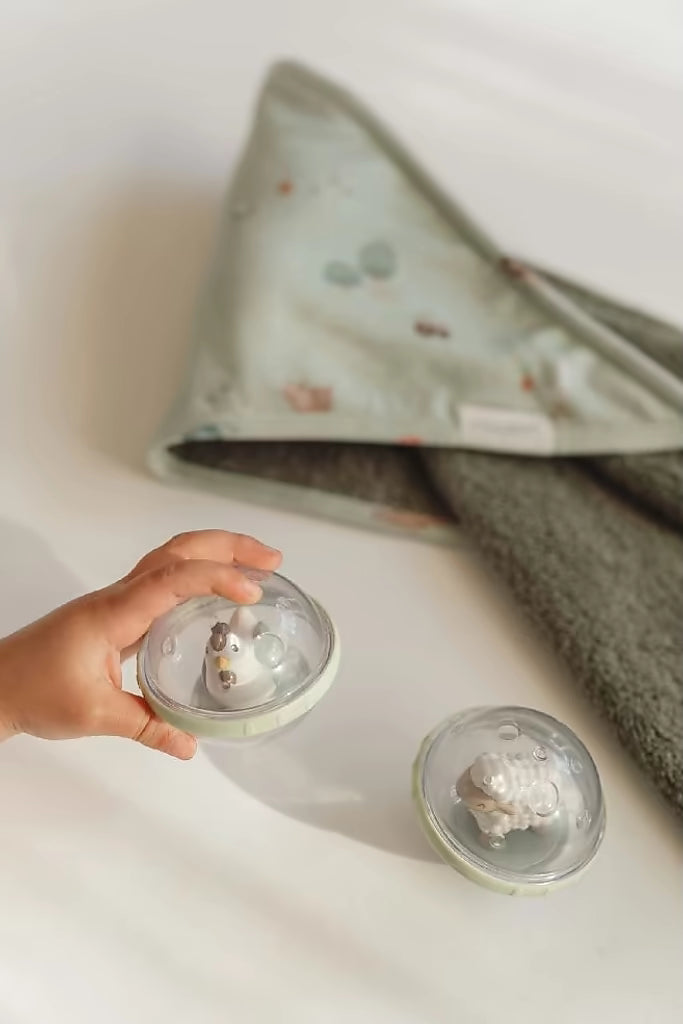 Little Dutch Roterende Ballen Farm speelgoed met kip en schaap naast groen dekentje, badspeelgoed geschikt voor baby.