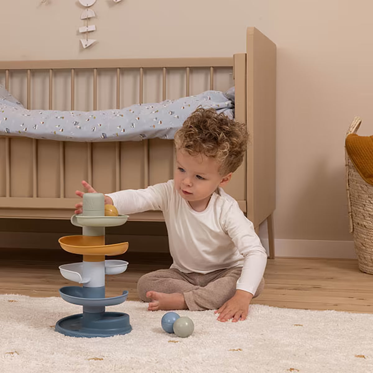 Kind speelt geconcentreerd met Little Dutch Spiraaltoren Blauw, een kleurrijke ballenbaan voor baby’s en peuters.