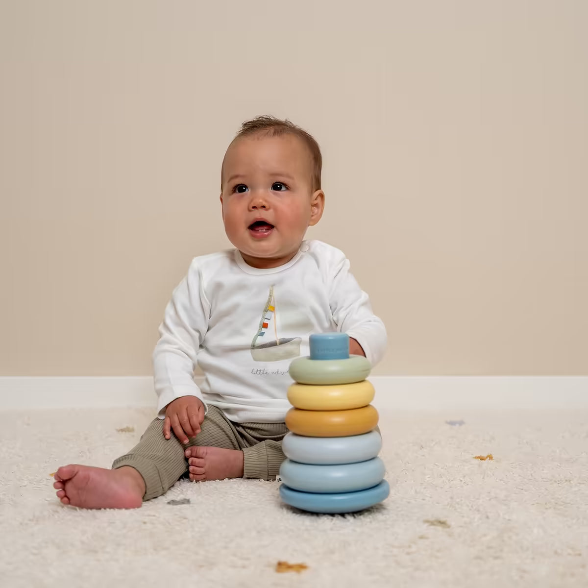 Baby speelt op vloerkleed met Little Dutch Stapelringen Blauw, stapeltoren baby speelgoed geschikt als cadeau.