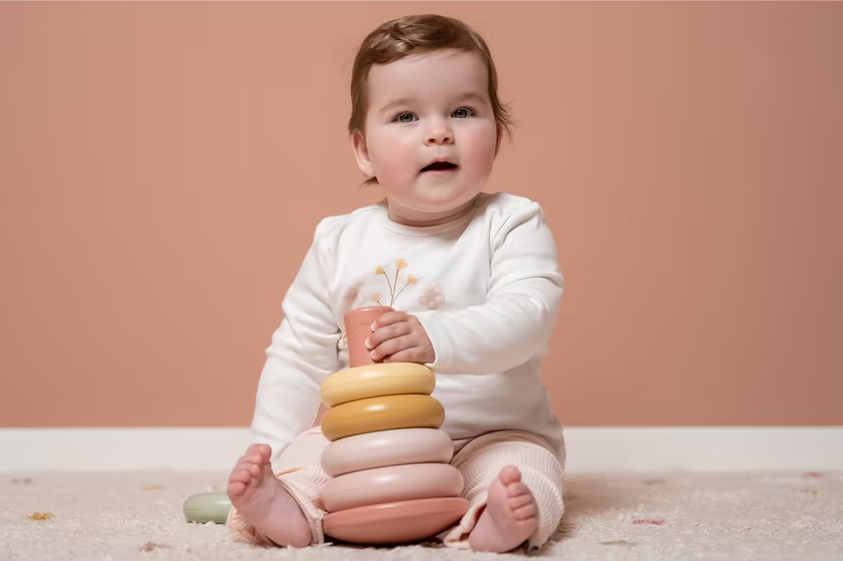 Baby houdt Little Dutch Stapelringen Roze vast, ideaal baby cadeau dat spelenderwijs leren stimuleert.