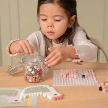 Kind pakt kralen uit pot en knutselt een figuur met Little Dutch Strijkkralen Maxi, creatieve knutsel ideeën.