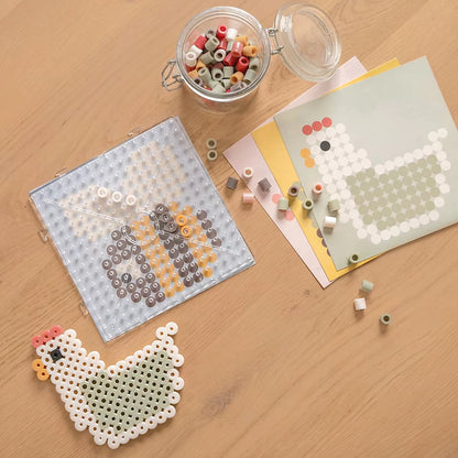 Bovenaanzicht strijkplaat met bij en voorbeeldkaarten naast kip, gemaakt met Little Dutch Strijkkralen Maxi Little Farm.