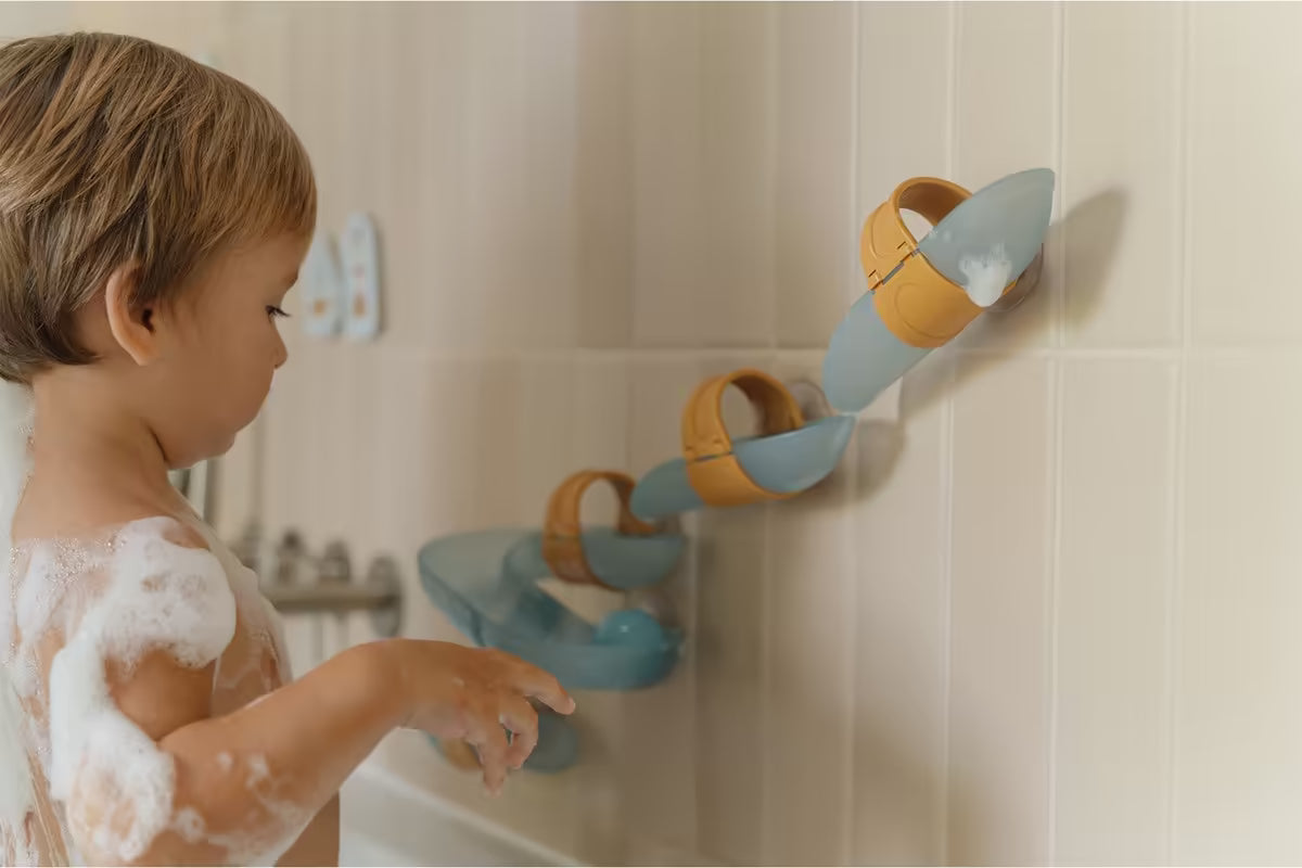 Kind speelt met Little Dutch Waterbaan Blauw in bad, vrolijk badspeelgoed dat stimuleert en waterpret vergroot.