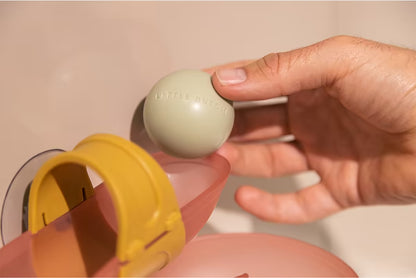 Hand plaatst een bal in de Little Dutch Waterbaan - Roze, detailfoto van badspeelgoed voor peuters.