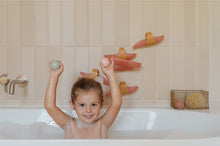 Peuter speelt in bad met Little Dutch Waterbaan - Roze en houdt vrolijk twee ballen omhoog tijdens het badmoment.