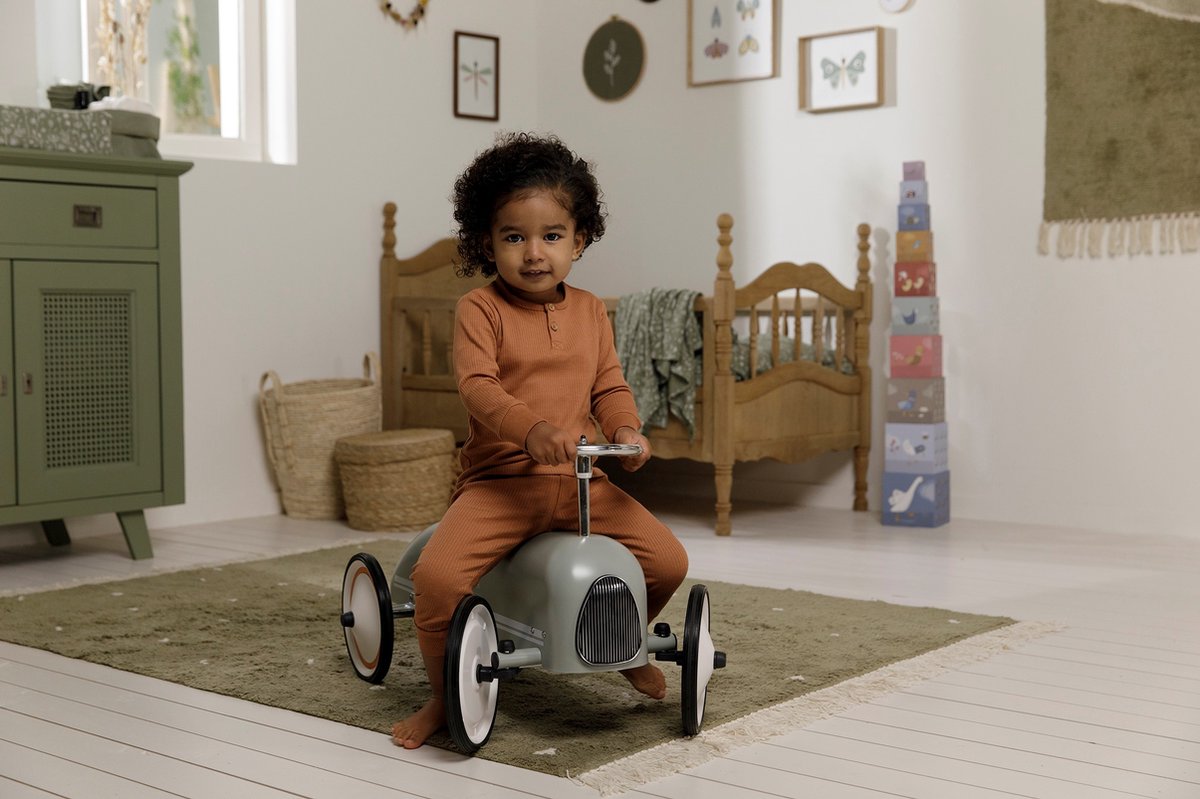Peuter speelt met Little Dutch retro loopauto in Scandinavische kinderkamer met houten speelgoed