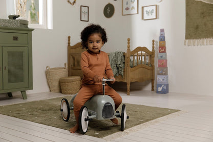 Peuter speelt met Little Dutch retro loopauto in Scandinavische kinderkamer met houten speelgoed