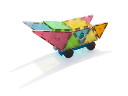 Een MAGNA-TILES Grand Prix-voertuig, gemaakt van doorschijnende tegels en wielen, werpt een schaduw op een wit oppervlak.