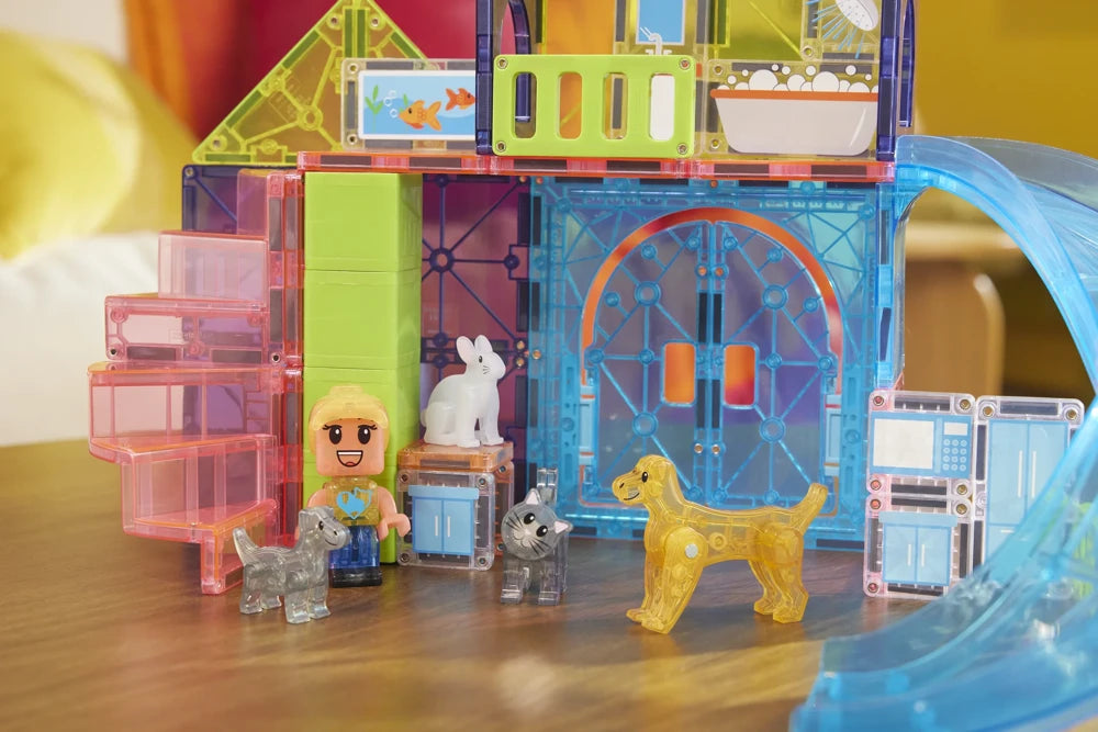 Magna Tiles Pet Playhouse op tafel met kind en dierenfiguren zoals hond, kat, konijn en transparante bouwstenen.