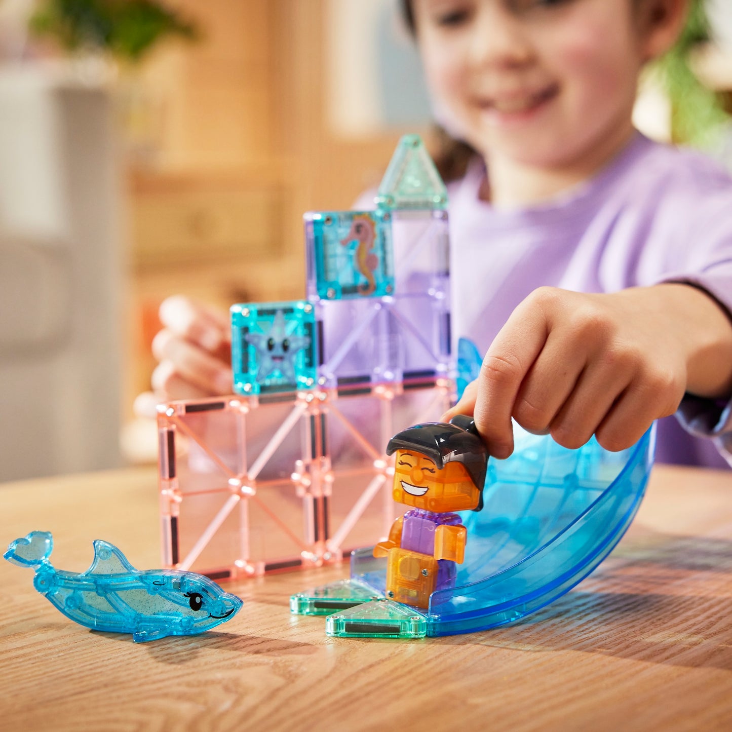 Magne Tiles Dolphin Bay speelset in actie met kind dat MicroMags tegels en figuren gebruikt bij glijbaan