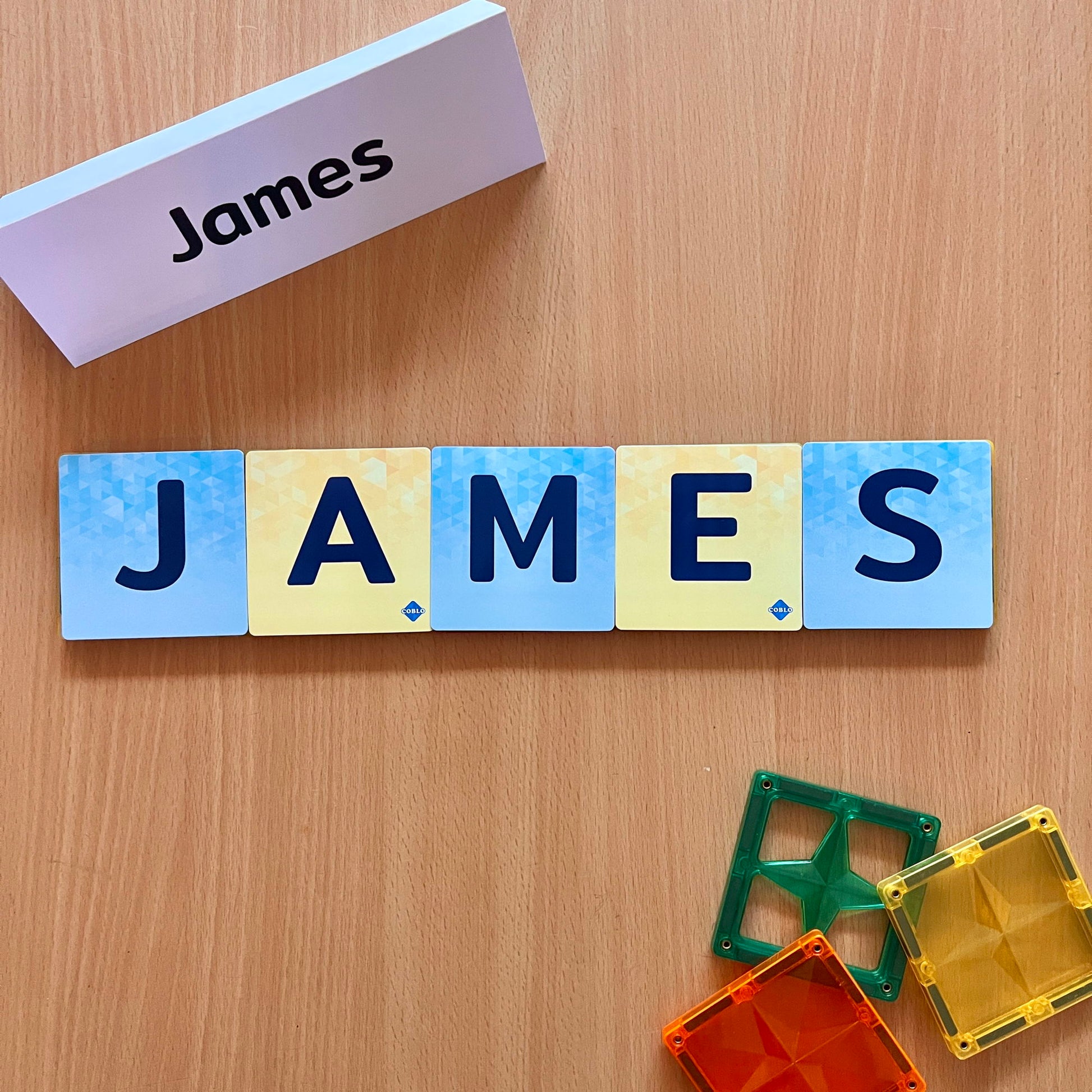 Magneet bouwstenen Coblo letters James met kleurrijke magnetische tegels op houten tafel