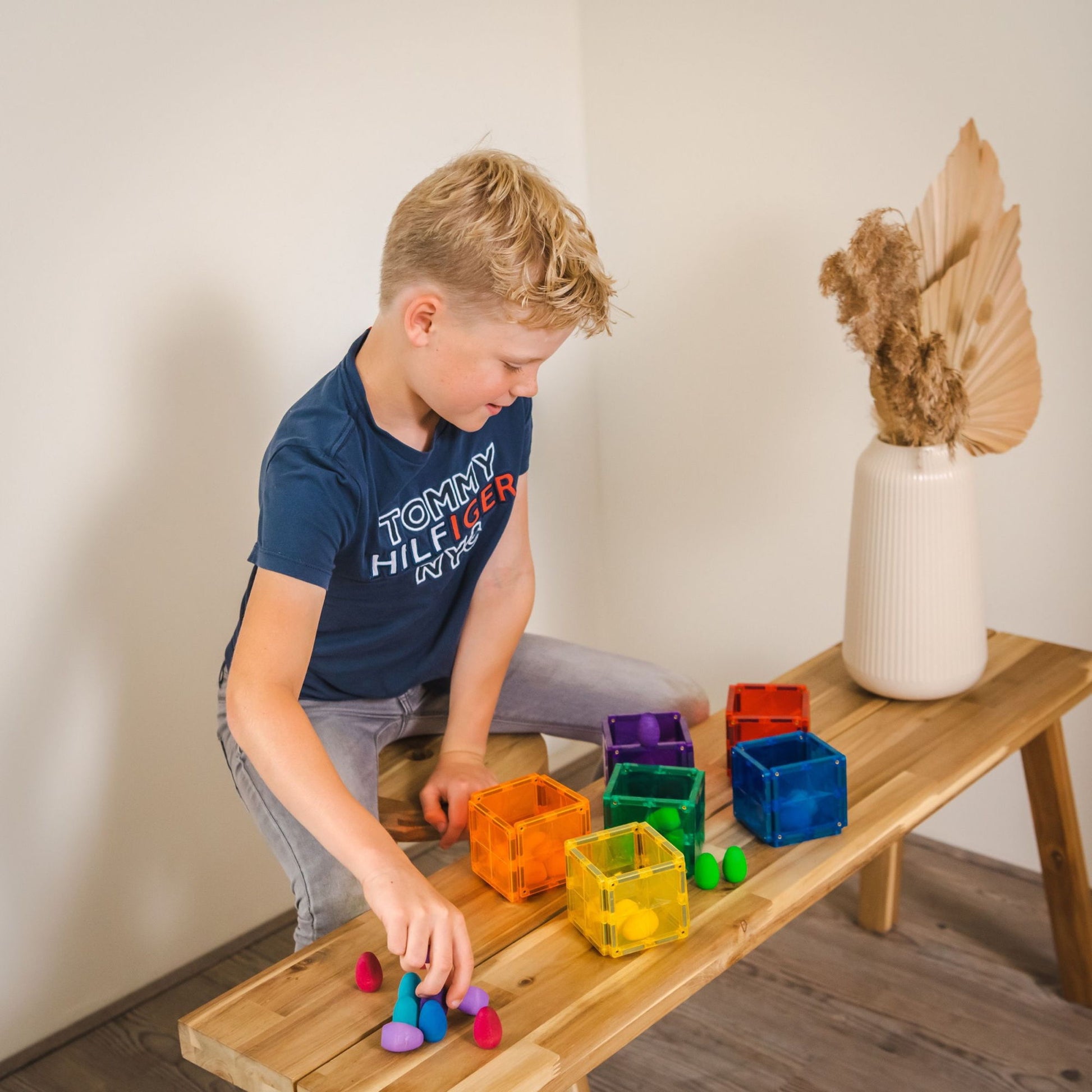 Magneet tegels Coblo - jongen speelt met gekleurde magnetische speelgoed kubussen op houten bankje