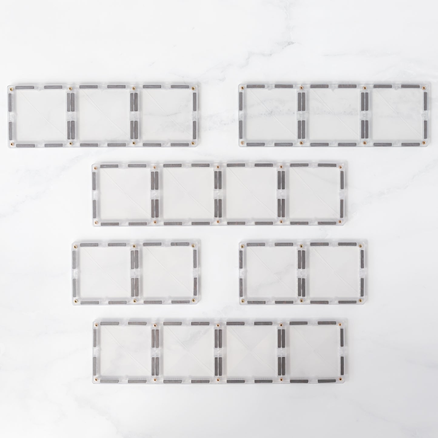 Bovenaanzicht alle 12 Connetix Clear Rectangle magnetische tegels plat uitgelegd marmeren witte ondergrond