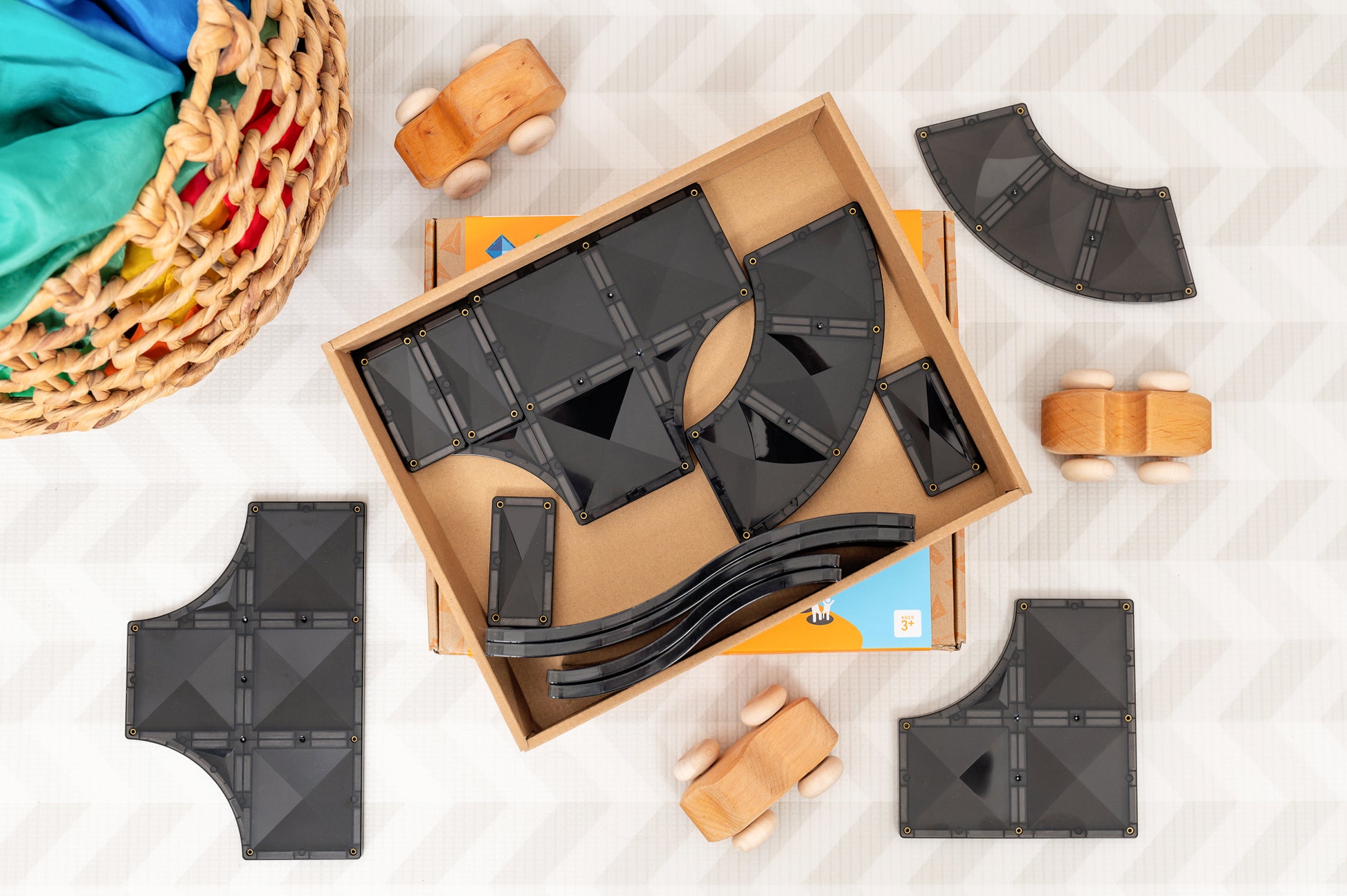 Magneet tegels Connetix Roads zwarte onderdelen in open doos met houten speelgoedaccessoires