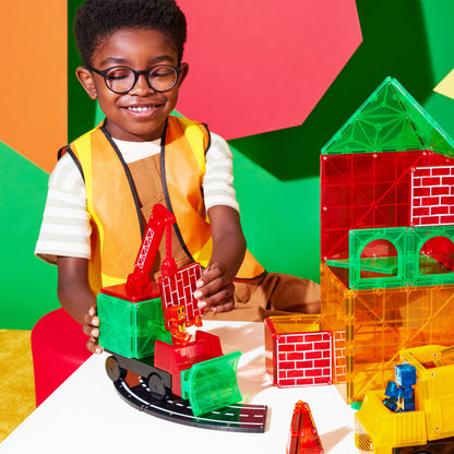 Kind speelt met magnetic magna tiles bouwset, constructievoertuigen en kleurrijke magnetische tegels