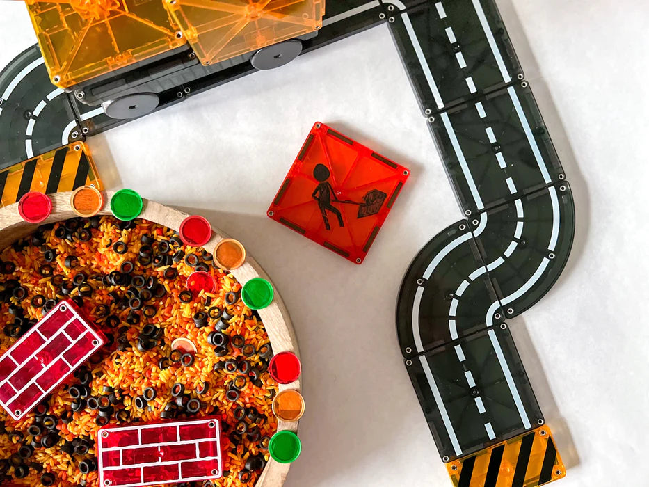 Een zeshoekig stuk van de Magnetic Magna Tiles Builder toont een wegwerkzaamheden afbeelding met wegdelen en rode bouwstenen.