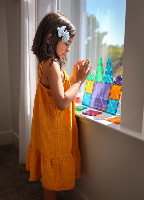 Meisje speelt bij het raam met Magnetic Magna Tiles Classic Set, 32 kleurrijke magnetische bouwstenen magneet speelgoed.