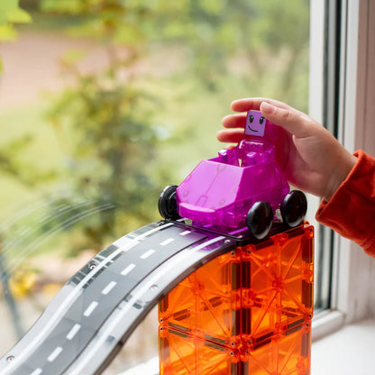 Een hand plaatst een paarse auto op de Magnetic Magna Tiles Downhill Duo, 40 magnetische bouwstenen in oranje, met racebaan.