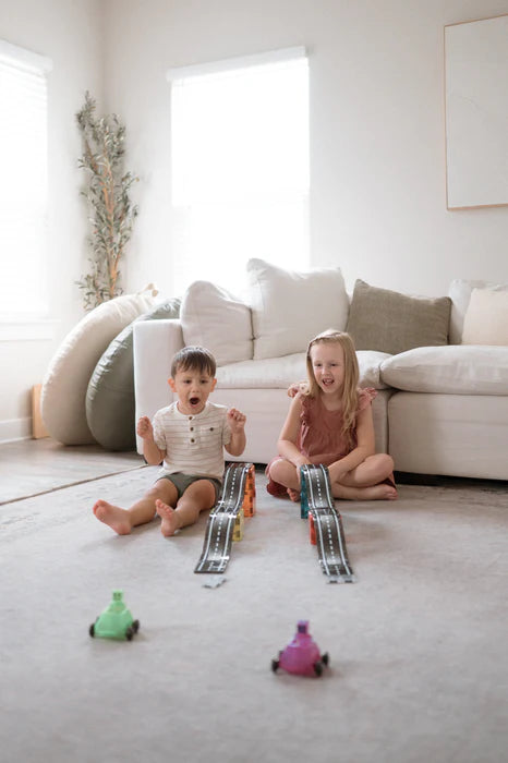 Twee kinderen spelen met autos en racebaan op de vloer van Magnetic Magna Tiles Downhill Duo, 40 magnetische bouwstenen.