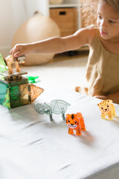 Meisje speelt met MicroMags Jungle Animals van Magna Tiles waaronder tijger, nijlpaard en luipaard op witte tafel.