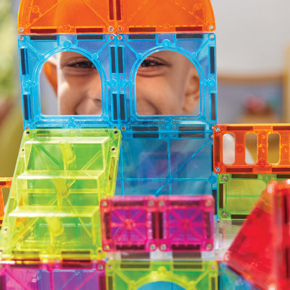 Magnetic magna tiles close-up kind kijkt door magneet speelgoed constructie met kleurrijke tegels
