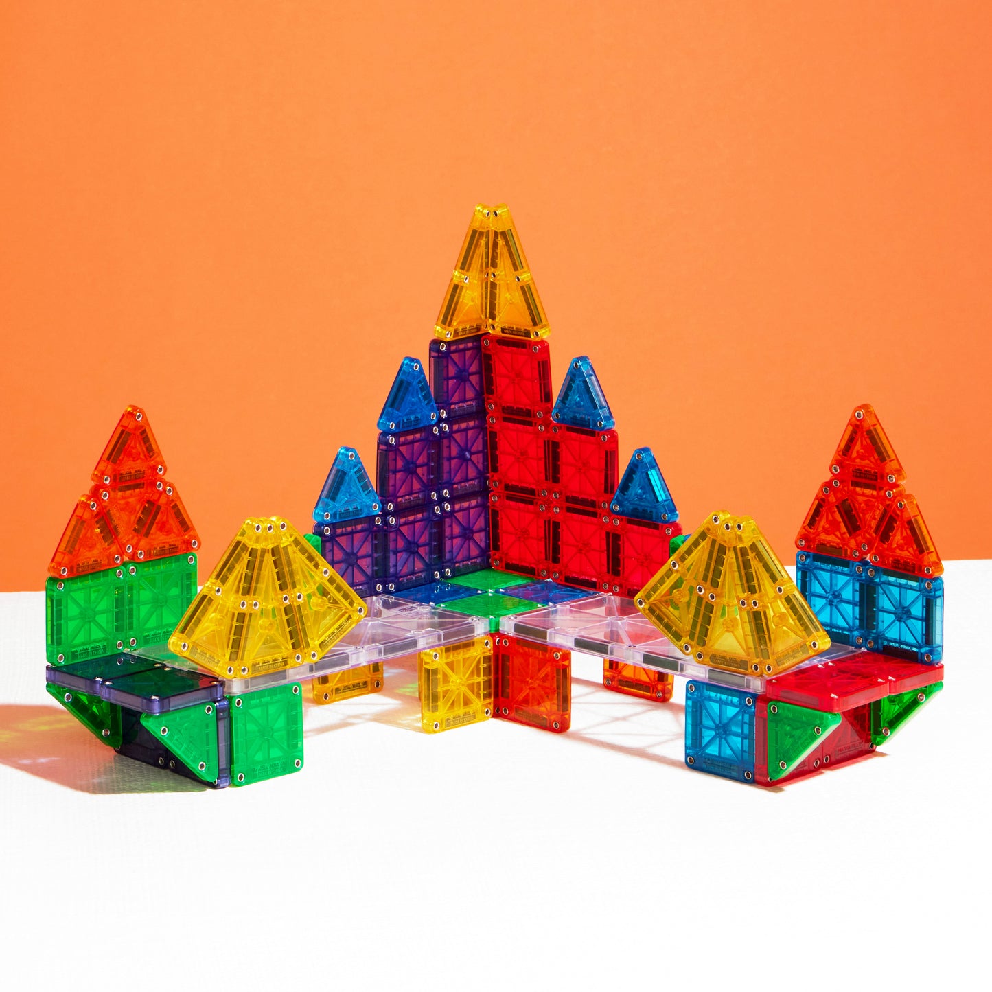 Magnetic magna tiles MicroMAGS bouwconstructies met kastelen in transparante kleuren op oranje achtergrond