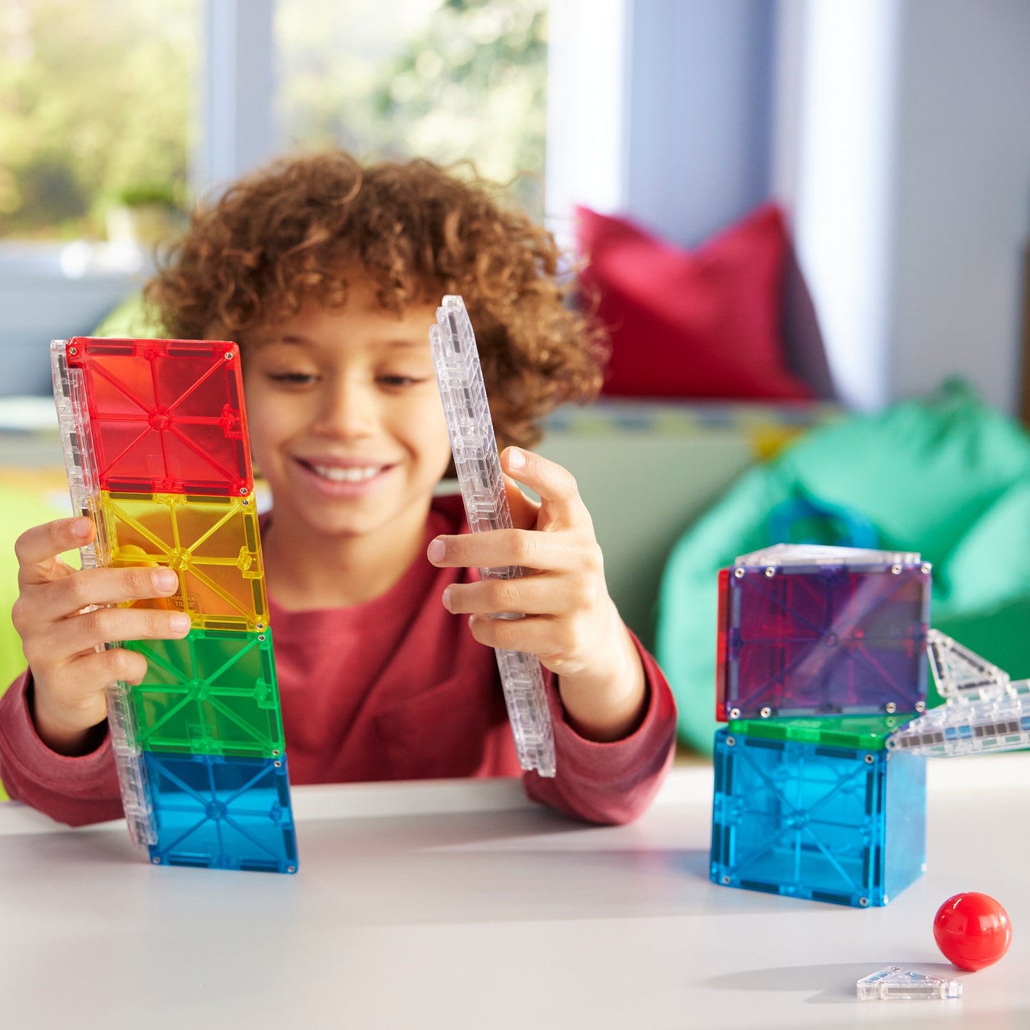 Kind toont magnetic magna tiles Rail Racers transparante knikkerbaan rail en gekleurde magnetische tegels