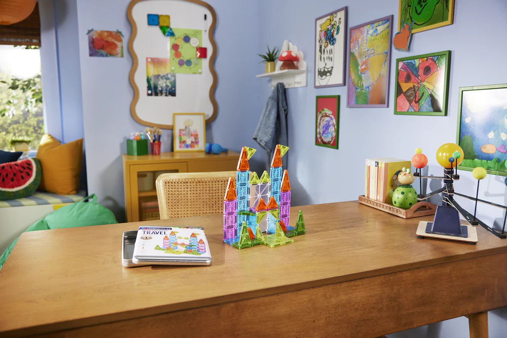 Magnetische tegels van Magna Tiles op speeltafel in kinderkamer met kleurrijke tekeningen en accessoires.