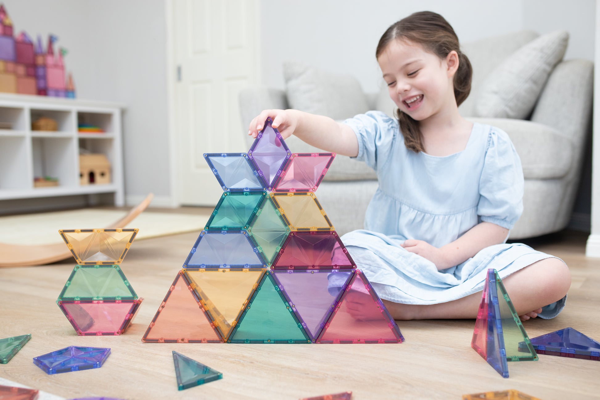 Meisje bouwt piramide met Connetix Pastel Shape Expansion Pack 48pc magnetisch speelgoed in woonkamer