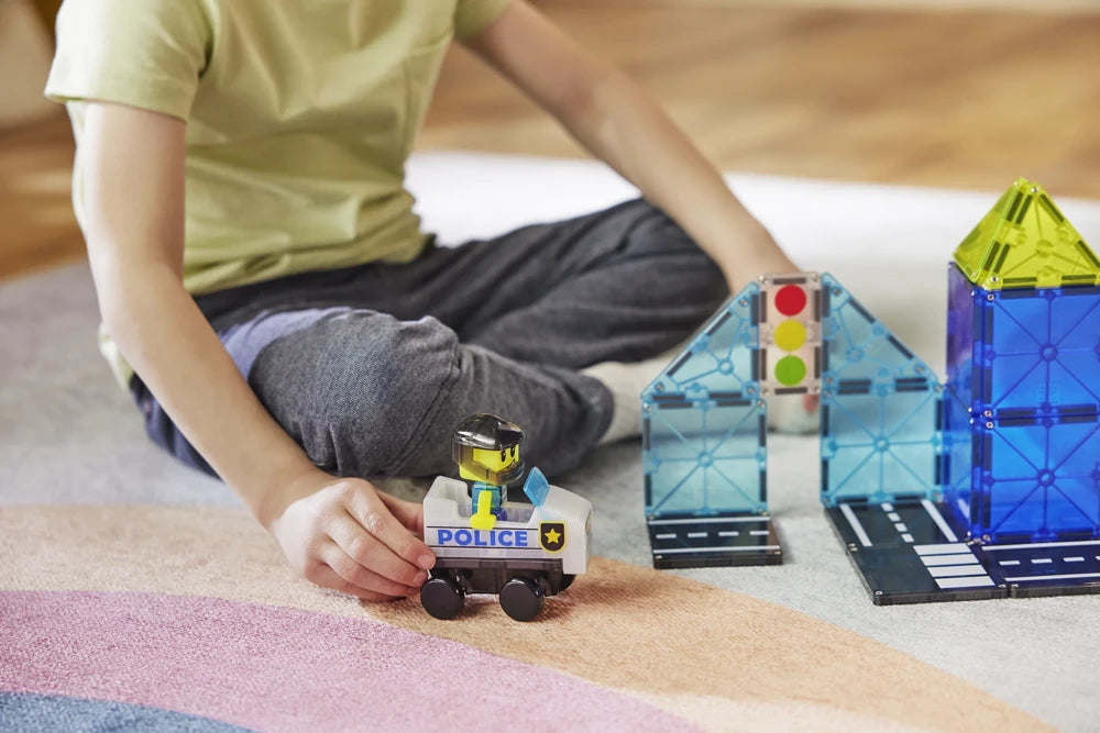 Kind bestuurt MicroMags politiewagen met magneet speelgoed en blauw-geel Police Patrol gebouw van Magna Tiles.