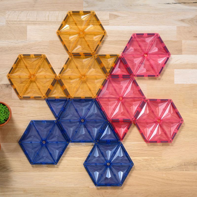 Bovenaanzicht magnetische bouwstenen Coblo hexagon in oranje, roze en blauw op houten ondergrond