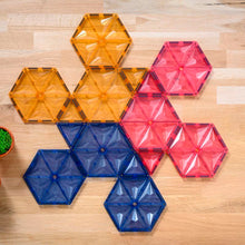 Bovenaanzicht magnetische bouwstenen Coblo hexagon in oranje, roze en blauw op houten ondergrond