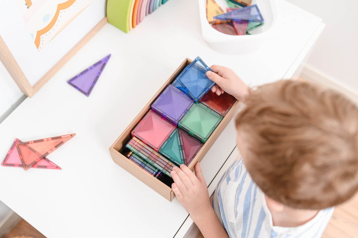 Kind opent doos Connetix Pastel Starter Pack 64pc met kleurrijke magnetische tegels, bovenaanzicht