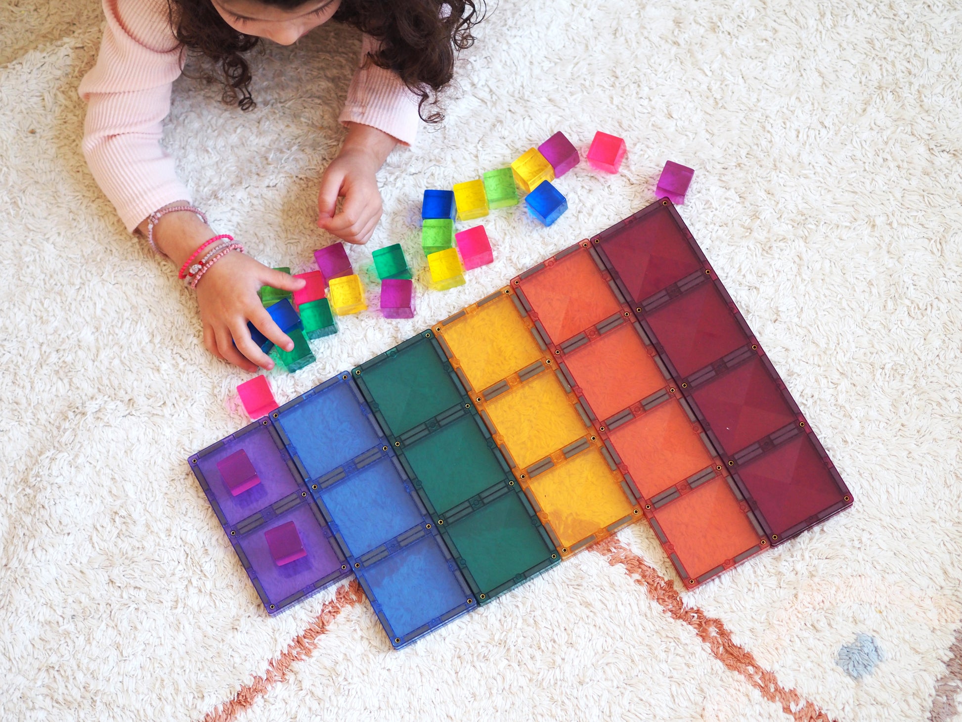 Meisje speelt met Connetix Pastel Rectangle Pack 24pc magnetische tegels op zacht vloerkleed