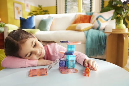 Jong meisje kijkt dromerig naar rode kat en kleurrijke Cat Tree speelset van Magna Tiles.