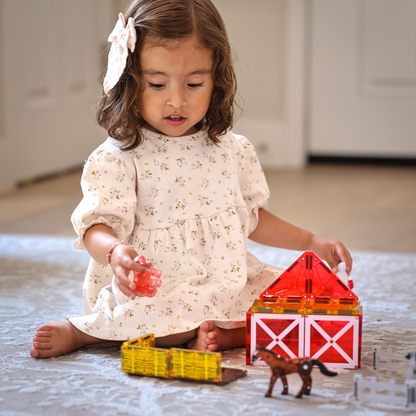 Meisje bouwt met magnetic magna tiles farm animals boerderij en magneet speelgoed op speelmat