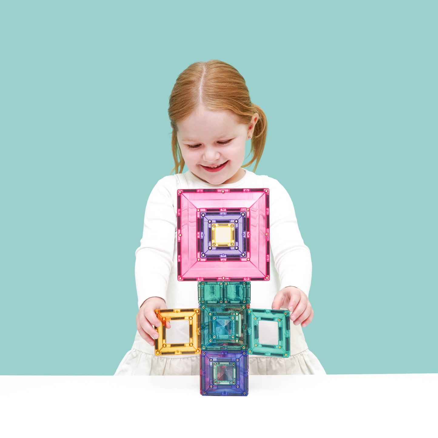 Blij meisje toont Connetix Pastel Portal Pack 48pc magnetische tegels op mintgroene studio achtergrond